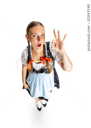 High angle view of sexy Oktoberfest woman, waitress wearing a traditional Bavarian or german dirndl isolated on white studio background. High angle view of sexy Oktoberfest woman, waitress wearing a traditional Bavarian or german dirndl isolated on white studio background. 82043540
