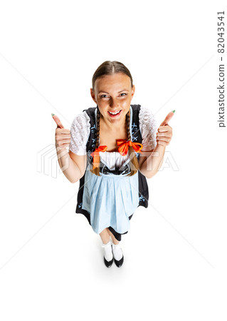 High angle view of sexy Oktoberfest woman, waitress wearing a traditional Bavarian or german dirndl isolated on white studio background. High angle view of sexy Oktoberfest woman, waitress wearing a traditional Bavarian or german dirndl isolated on white studio background. 82043541