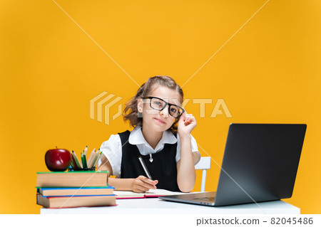Caucasian schoolgirl in glasses sitting at laptop during online lesson. Distant School Learning. Caucasian schoolgirl in glasses sitting at laptop during online lesson. Distant School Learning. 82045486