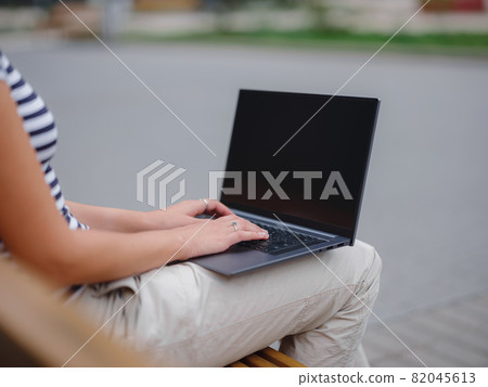 student working at laptop sit down on bench on urban city street. student working at laptop sit down on bench on urban city street. 82045613
