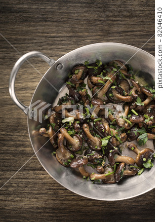 Shiitake mushrooms sauteed with garlic and herbs in metal pan Shiitake mushrooms sauteed with garlic and herbs in metal pan 82046410