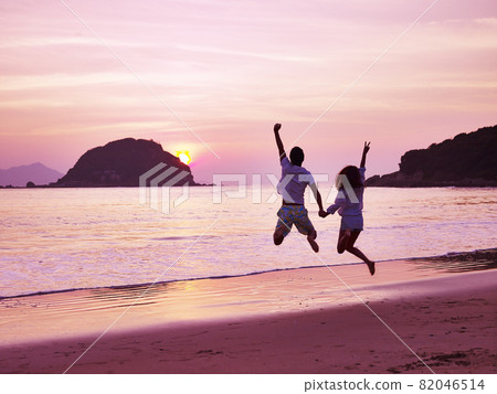 young asian couple cheering and rejoicing on beach as the sun rising 82046514
