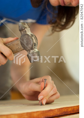 Female hands are using claw hammer and nail for making wooden bench, gender equality, feminism, do it yourself concepts. Female hands are using claw hammer and nail for making wooden bench, gender equality, feminism, do it yourself concepts. 82047042