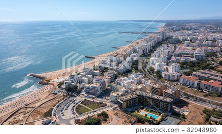Beautiful aerial cityscapes of the tourist Portuguese city of Quarteira. On the seashore during the beach season with tourists who are sunbathing. Beautiful aerial cityscapes of the tourist Portuguese city of Quarteira. On the seashore during the beach season with tourists who are sunbathing. 82048980