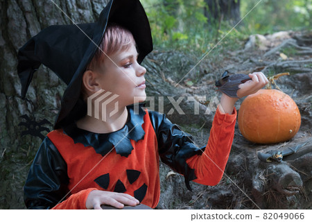 The witch admires her handmade bat. A girl dressed for Halloween is holding her pet, a rattle mouse, in her hand. Beautiful stylish picture for Halloween 82049066