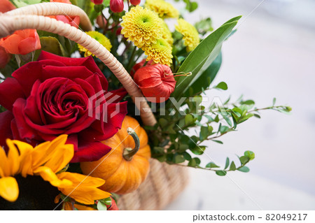Close-up of a basket with beautiful autumn flowers made of red roses, sunflowers and green leaves. The concept of the holiday. Copy space. High quality photo Close-up of a basket with beautiful autumn flowers made of red roses, sunflowers and green leaves. The concept of the holiday. Copy space. High quality photo 82049217