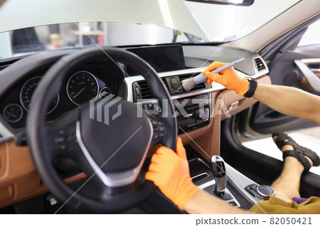 Manual cleaning of car interior with brush for hard-to-reach places in dashboard closeup Manual cleaning of car interior with brush for hard-to-reach places in dashboard closeup 82050421