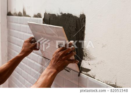 Worker putting tiles on the wall. 82051548