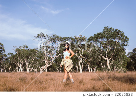 Portrait of traveler young asian woman standing and cross arm on sunset time in the summer forest,Happy and smiling,Relaxing time,Travel and vacation concept 82055828