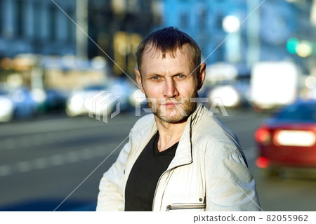 Face of serious bearded man of about 40 on background of city street. 82055962