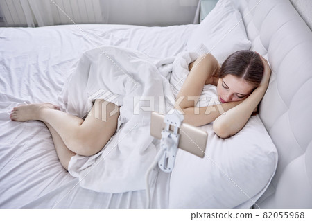 Hands Free smartphone holder fastened near bed with sleeping young woman. Hands Free smartphone holder fastened near bed with sleeping young woman. 82055968