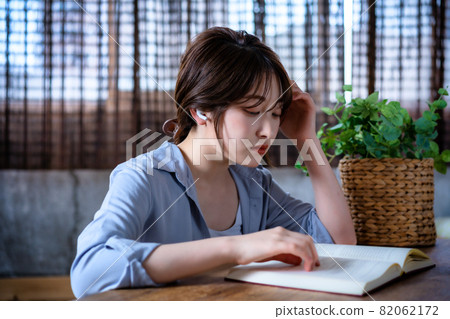 戴著耳機看書的年輕女人 82062172