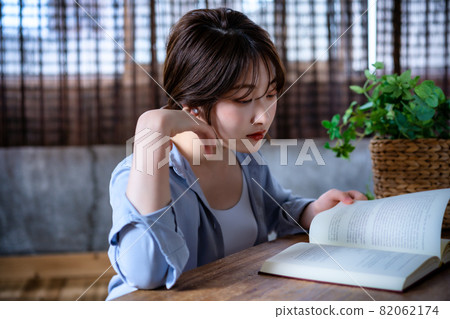 戴著耳機看書的年輕女人 戴著耳機看書的年輕女人 82062174