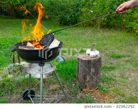 Freshly lit barbecue fire with logs of burning wood over small chips of kindling in a portable BBQ Freshly lit barbecue fire with logs of burning wood over small chips of kindling in a portable BBQ 82062292