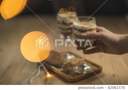 A wine glass fill with cream and crumb serve on a wooden plate with blurry background. A wine glass fill with cream and crumb serve on a wooden plate with blurry background. 82062370