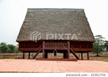 A tourist exploring a traditional architecture of a Bahnar ethnic stilt house or Rong House in Pleiku countryside, Vietnam A tourist exploring a traditional architecture of a Bahnar ethnic stilt house or Rong House in Pleiku countryside, Vietnam 82062709