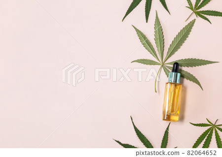 Natural cosmetic. Herbal Alternative Medicine Concept. Cannabis face serum or oil dropper concept and hemp leaves on beige background. Top view flat lay. Copy space. 82064652