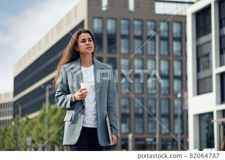 Young beautiful business woman at casual clothes near office centre with cup of coffee. Lunch break among working day. Business lifestyle and success concept. 82064787