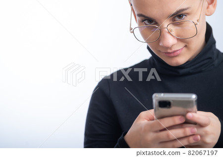 Young caucasian woman with short hair uses a smartphone on a white background. Young caucasian woman with short hair uses a smartphone on a white background. 82067197