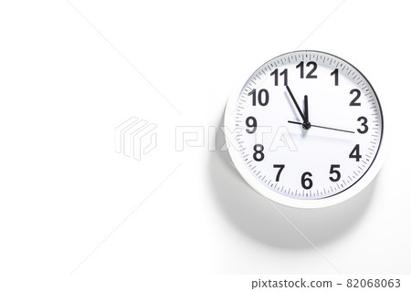It is five to twelve, the clock is ticking. White Watch shows the time 5 before 12. Close up to a wall clock, with five minutes to twelve o'clock. Time is running out. White background with copy space 82068063