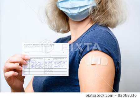 Vaccinated young woman in mask showing COVID-19 Vaccination Record Card Vaccinated young woman in mask showing COVID-19 Vaccination Record Card 82068336