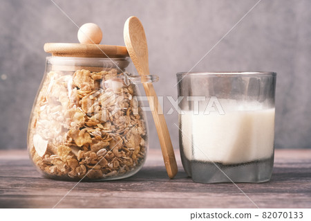 muesli with dried fruit in a jar with glass of milk on table, 82070133