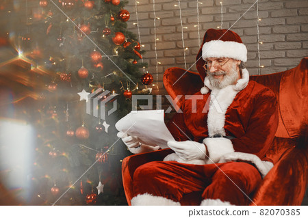 Man in santa claus costume sitting on a chair Man in santa claus costume sitting on a chair 82070385