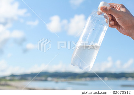 A plastic bottle on hand on a hot beach day A plastic bottle on hand on a hot beach day 82070512