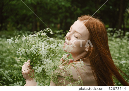 Healing Power of Nature, Benefits Of Ecotherapy, Nature Impact Wellbeing. Happy Redhead woman holding white wildflowers, relaxing and enjoying life on green nature background Healing Power of Nature, Benefits Of Ecotherapy, Nature Impact Wellbeing. Happy Redhead woman holding white wildflowers, relaxing and enjoying life on green nature background 82072344