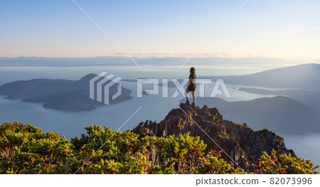 Adventurous Caucasian Woman Hiking on top of a Rocky Mountain Cliff. Adventurous Caucasian Woman Hiking on top of a Rocky Mountain Cliff. 82073996