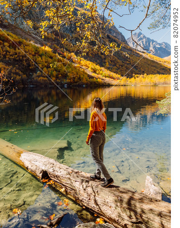 Traveller woman at transparent lake in the autumnal mountain. Traveller woman at transparent lake in the autumnal mountain. 82074952