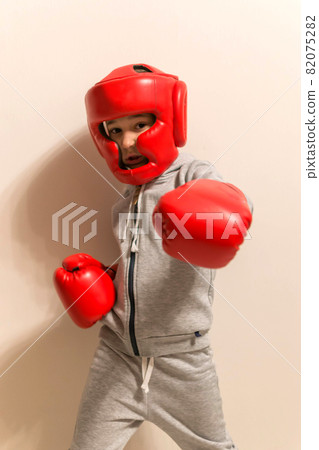 Young boy boxer in red boxing gloves kick Young boy boxer in red boxing gloves kick 82075282