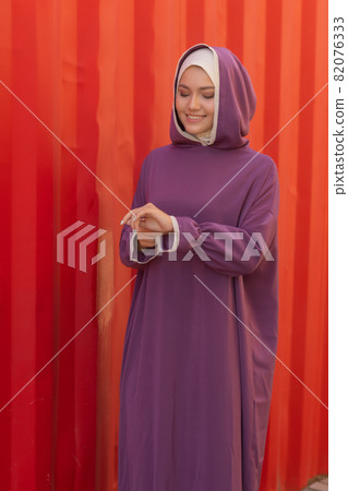 Islamic beautiful woman in a Muslim dress standing on a summer park street background forest autumn trees.world hijab day. Islamic beautiful woman in a Muslim dress standing on a summer park street background forest autumn trees.world hijab day. 82076333