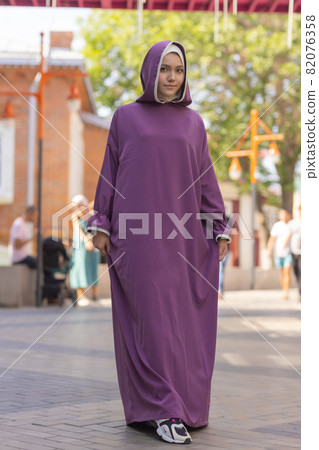 Islamic beautiful woman in a Muslim dress standing on a summer park street background forest autumn trees.world hijab day. Islamic beautiful woman in a Muslim dress standing on a summer park street background forest autumn trees.world hijab day. 82076358