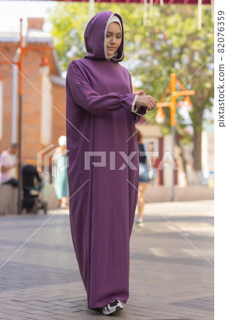 Islamic beautiful woman in a Muslim dress standing on a summer park street background forest autumn trees.world hijab day. Islamic beautiful woman in a Muslim dress standing on a summer park street background forest autumn trees.world hijab day. 82076359