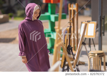 Islamic beautiful woman in a Muslim dress standing on a summer park street background forest autumn trees.world hijab day. Islamic beautiful woman in a Muslim dress standing on a summer park street background forest autumn trees.world hijab day. 82076372
