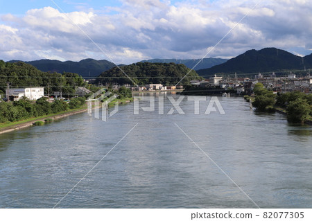 Electric wires seen from the viaduct, rivers on the river surface of ripples, promenades, towns, green trees, roads, mountains, clouds of various colors and shapes, and the scenery of the blue sky 82077305