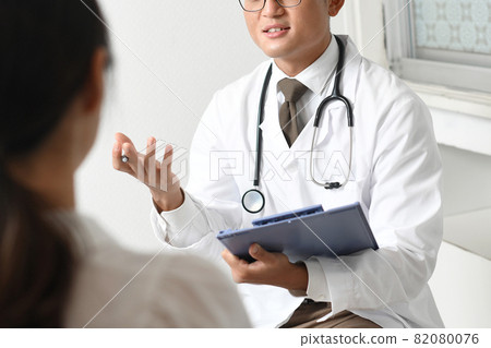 A smiling young male doctor in a white coat (medical worker / doctor) 82080076