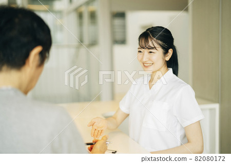 Woman (patient) at the reception desk of the hospital Woman (patient) at the reception desk of the hospital 82080172