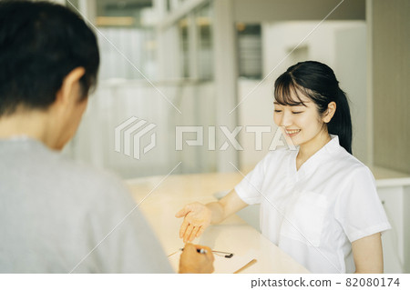Woman (patient) at the reception desk of the hospital Woman (patient) at the reception desk of the hospital 82080174