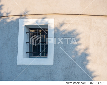 Window with iron bars on the wall of the old fort. Historical windmill Window with iron bars on the wall of the old fort. Historical windmill 82083715