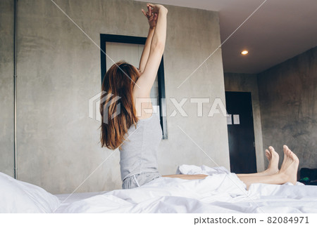 Portrait of young Asian woman raised her hands and stretching in bed after her waking up in the morning. Conceptual of woman lifestyle. Portrait of young Asian woman raised her hands and stretching in bed after her waking up in the morning. Conceptual of woman lifestyle. 82084971