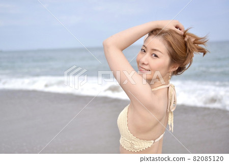 Young woman in swimsuit posing on the beach 82085120