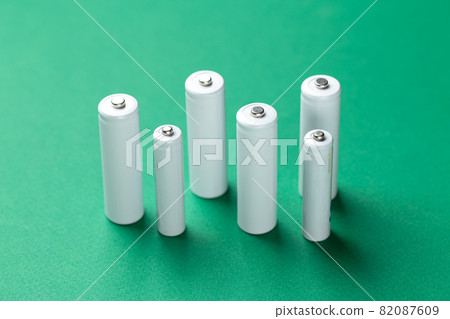 Several AA batteries in  close up on a green background. Alkaline battery. 82087609