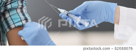 Nurse making injection of medicine into patient shoulder in clinic closeup 82088076