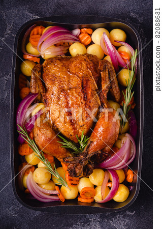 Whole baked chicken with vegetables. 82088681