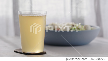 closeup ginger beer in a tumbler glass on oak table with blue bowl on background closeup ginger beer in a tumbler glass on oak table with blue bowl on background 82088772