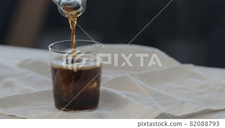 man pour cola over ice rocks into tumbler glass 82088793