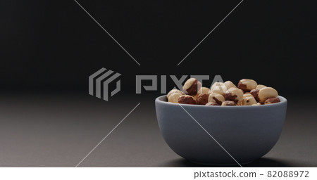 roasted hazelnuts in blue bowl on black background 82088972