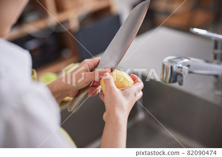 在廚房裡去除土豆芽的年輕女人 82090474
